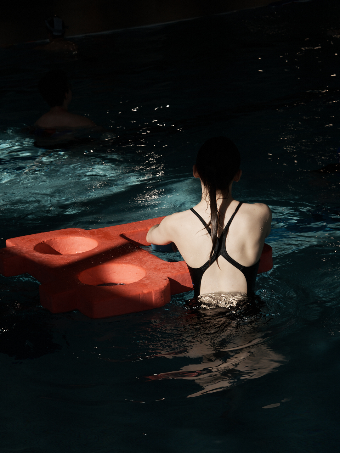 Photographie sombre et dramatique d'une nageuse en clair obscur